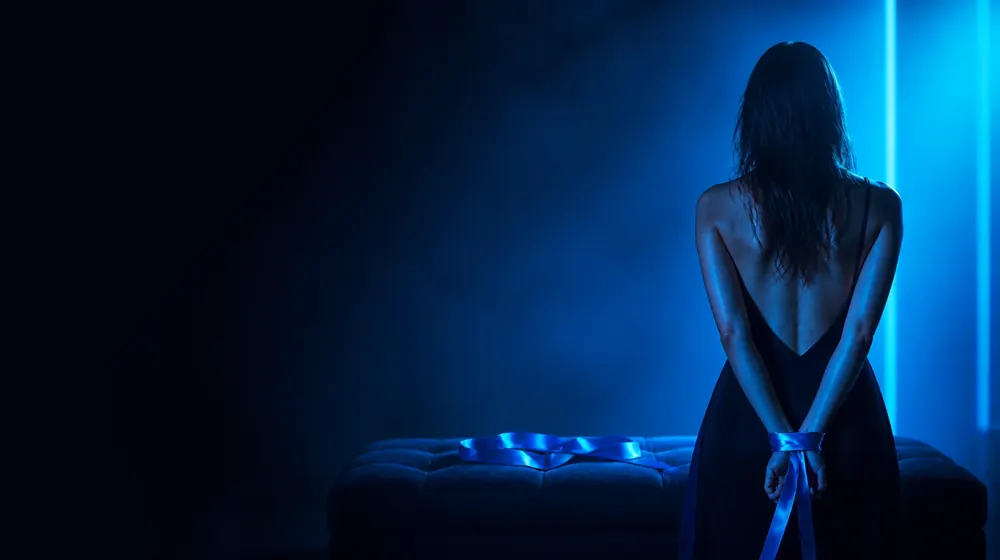 Bare Bottom Spanking OnlyFans creators — woman with a silk ribbon around her wrists in neon light, a velvet bench and folded silk ribbon waiting