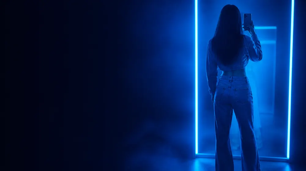 Booty On OnlyFans creators — woman in a fitted evening dress in neon rim light, a mirror selfie stance in high-waist jeans