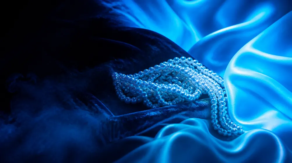 Bukakke OnlyFans creators — silk fabric rippling in cool blue light, pearl ropes pooled in the velvet tray