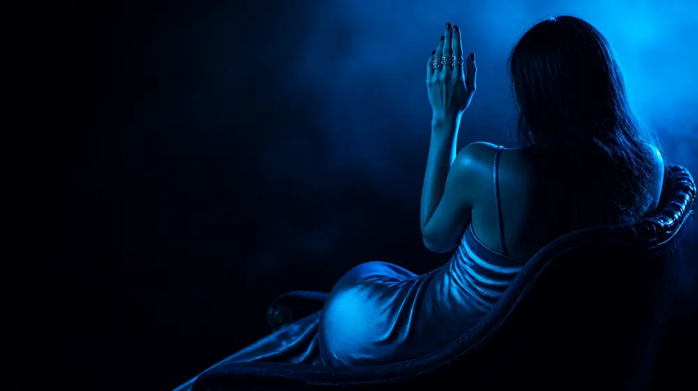 Fingering OnlyFans creators — woman in a silk slip dress reclining on a chaise longue, rings stacked on two raised fingers